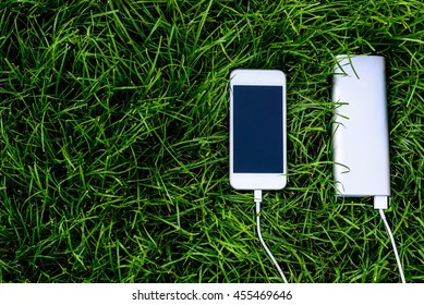 Powerbank Charging White Smartphone On Grass