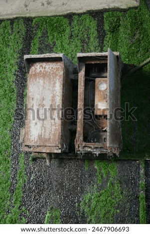 Powerbox behind a wall separating water and land, water leaks from the wall, on the electricity box