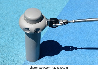 Powercoated steel anchor post or bollard in playground with stainless steel turnbuckle tie and hook. light blue soft granular sport flooring. safety floor. treaded adjustable metal turnbuckle. 