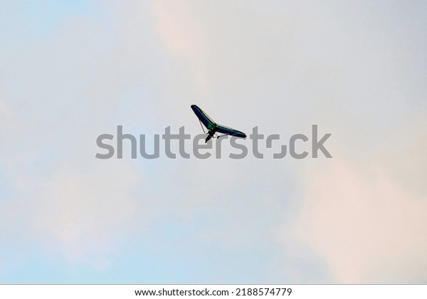 Powered hang glider flying in blue sky, motorized\
hang glider, ultralight trike overhead view, copy space. Tourist\
flight on foot-launched powered hang glider. Extreme tourism,\
extreme sports concept