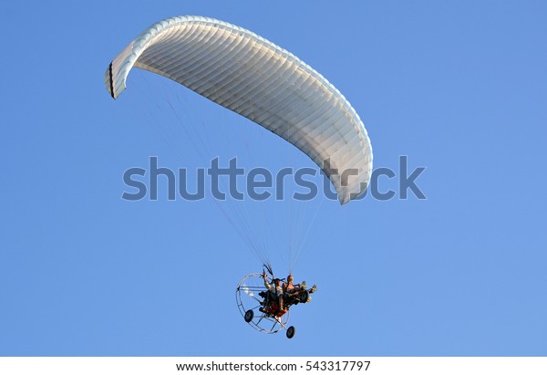 Powered parachute against\
the blue sky