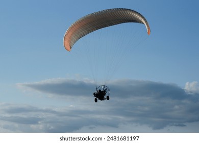 Powered paraglider flying against the blue sky - Powered by Shutterstock