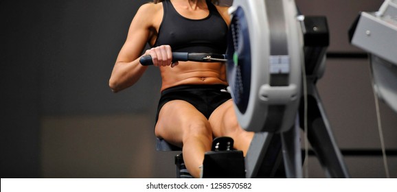 Powerful Attractive Muscular Woman CrossFit Trainer Do Workout On Indoor Rower At The Gym