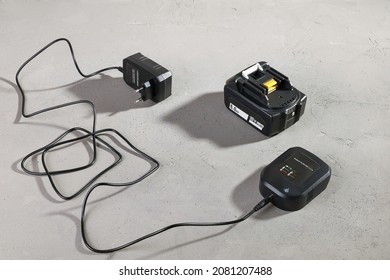 Powerful battery for electrical tool with disconnected charger on concrete gray surface