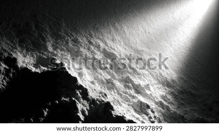 A powerful beam of light cuts through darkness, highlighting the rugged, textured surface of an asteroid or celestial body.