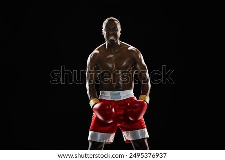 Powerful boxer with serious expression, showing his readiness to fight and win isolated on black background. Concept of professional sport, active lifestyle, body, strength