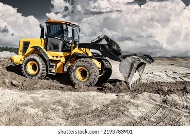 Powerful bulldozer or loader moves the earth at the construction site against the sky. An earthmoving machine is leveling the site. Construction heavy equipment for earthworks - Shutterstock ID 2193783901