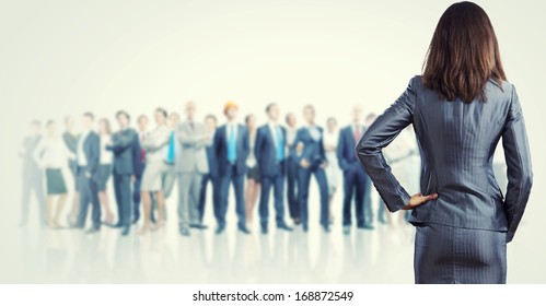 Powerful businesswoman standing with back with business team at background