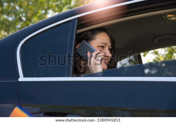 Powerful businesswoman using mobile phone in a\
backseat os a\
limousine