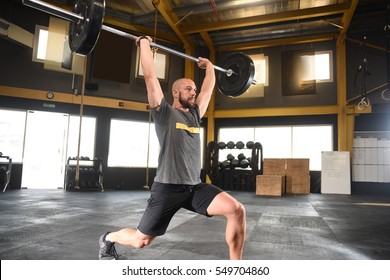 Powerful Crossfit Athlete In A Over-head Lunge With A Heavy Weight In A Cross-fit Box Gym 