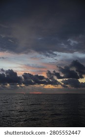 Powerful Dark Clouds Hanging Over the Ocean Horizon with Colorful Sunset Twilight Sky
