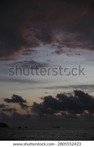 Powerful Dark Clouds Hanging Over the Ocean Horizon with Colorful Sunset Twilight Sky
