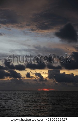Powerful Dark Clouds Hanging Over the Ocean Horizon with Colorful Sunset Twilight Sky
