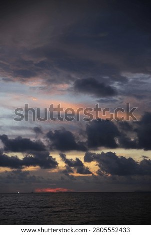 Powerful Dark Clouds Hanging Over the Ocean Horizon with Colorful Sunset Twilight Sky
