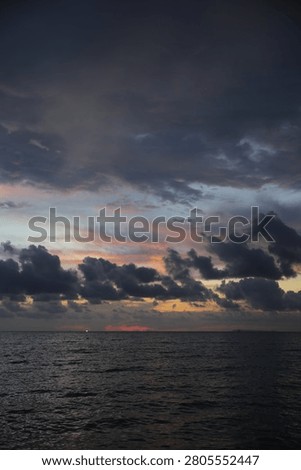 Powerful Dark Clouds Hanging Over the Ocean Horizon with Colorful Sunset Twilight Sky
