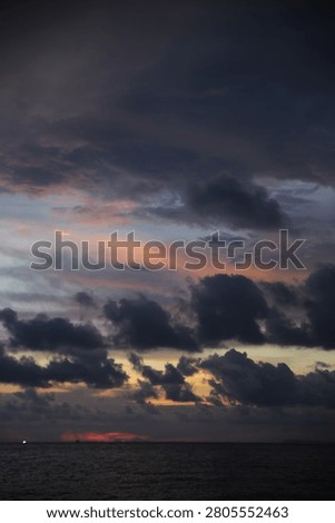 Powerful Dark Clouds Hanging Over the Ocean Horizon with Colorful Sunset Twilight Sky
