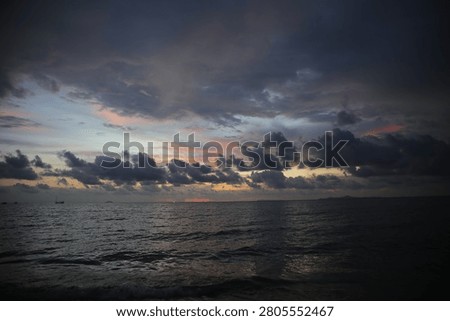 Powerful Dark Clouds Hanging Over the Ocean Horizon with Colorful Sunset Twilight Sky
