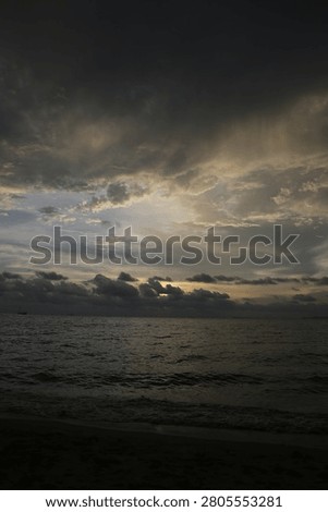 Powerful Dark Clouds Hanging Over the Ocean Horizon with Colorful Sunset Twilight Sky

