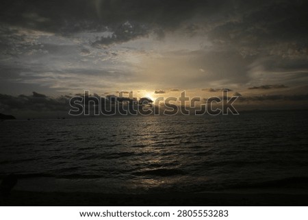 Powerful Dark Clouds Hanging Over the Ocean Horizon with Colorful Sunset Twilight Sky

