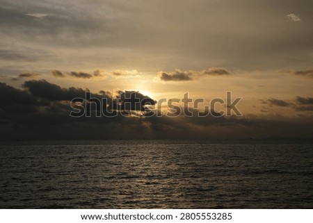 Powerful Dark Clouds Hanging Over the Ocean Horizon with Colorful Sunset Twilight Sky
