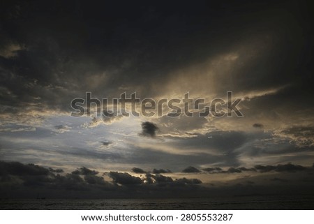 Powerful Dark Clouds Hanging Over the Ocean Horizon with Colorful Sunset Twilight Sky
