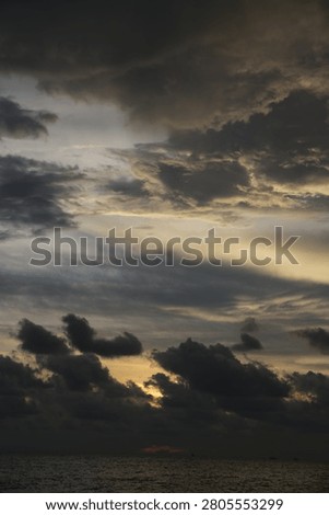 Powerful Dark Clouds Hanging Over the Ocean Horizon with Colorful Sunset Twilight Sky
