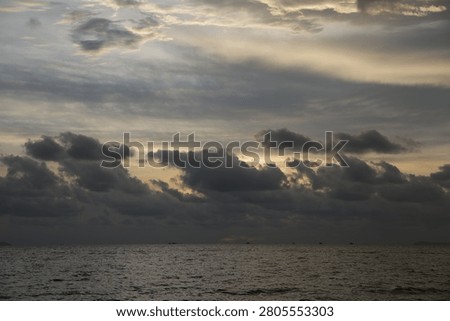 Powerful Dark Clouds Hanging Over the Ocean Horizon with Colorful Sunset Twilight Sky

