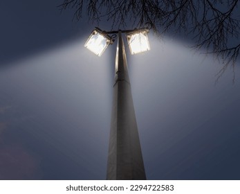 Powerful and economical LED city lights on a metal pole against dark sky. Town and sport event illumination concept.