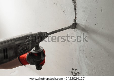 Powerful electric hammer drill for drilling and scoring a concrete wall - room finishing electrical wiring