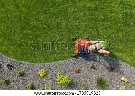 Powerful Gasoline Lawn Aerator Job For Controlling Lawn Thatch, And Reducing Soil Compaction. Backyard Grass Field Maintenance. Caucasian Gardener in His 40s. Aerial View.