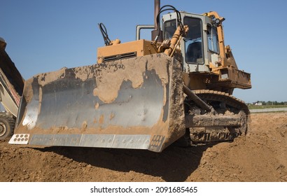 Powerful Heavy Crawler Bulldozer Works At A Construction Site On A Hot Sunny Day. Construction Equipment For Earthworks. Dozer Blade Close Up