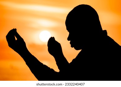 A powerful image capturing the silhouette of a devout Christian, his hands raised high in prayer as the solstice sunset casts a warm glow over him.