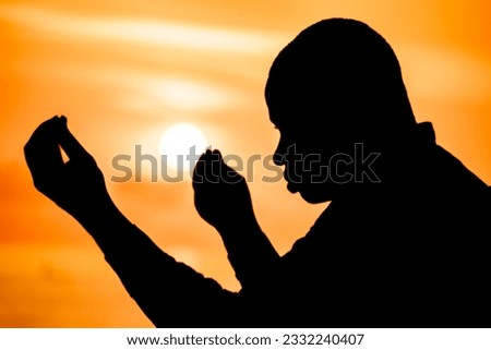 A powerful image capturing the silhouette of a devout Christian, his hands raised high in prayer as the solstice sunset casts a warm glow over him.