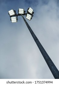 Powerful LED light on a metal pole turned on, cloudy sky background. Concept sport event, game.