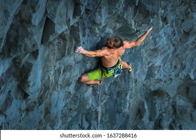Powerful Male Rock Climber Climbing On A Vertical Rock Face