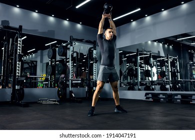 A Powerful Man Lifts A Kettle Bell Above His Head In The Fitness Center With Strong Movements.The Concept Of Functional Cross-fit Training. Energy Boost