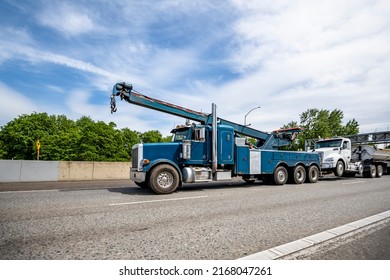 Powerful Mobile Helper Heavy Duty Blue Big Rig Towing Semi Truck Tractor With Extended Arrow Tow Out Of Service Elevated Broken Semi Truck To Auto Repair Shop Running On The Highway Road