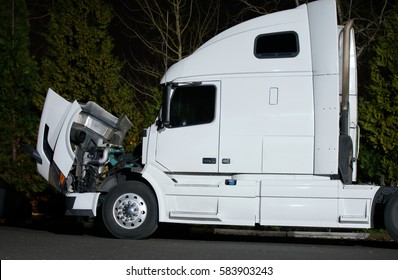 Powerful modern white semi-truck with the open hood standing evening on parking lot. The hot engine needs to be repaired and cooled by natural air flow for safety mechanic access.