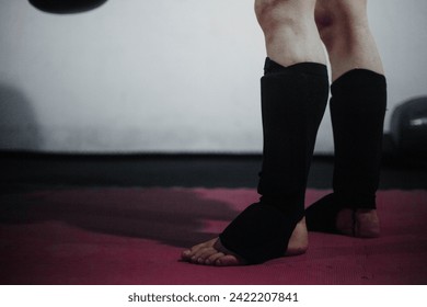 Powerful Muay Thai fighters' legs, shielded by shin guards, showcase strength and determination during an intense training session in the Thai martial art. - Powered by Shutterstock