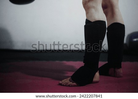 Powerful Muay Thai fighters' legs, shielded by shin guards, showcase strength and determination during an intense training session in the Thai martial art.
