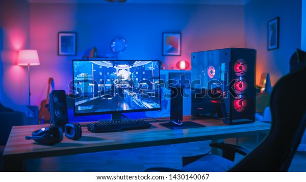 Powerful Personal\
Computer Gamer Rig with First-Person Shooter Game on Screen.\
Monitor Stands on the Table at Home. Cozy Room with Modern Design\
is Lit with Pink Neon\
Light.