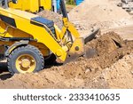 The powerful pneumatic sliding bucket of the wheeled bulldozer works on the leveling of the earthen working platform.