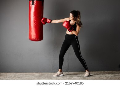 Powerful Punch. Full Length Shot Of An Attractive Young Female Boxer Training In The Gym.