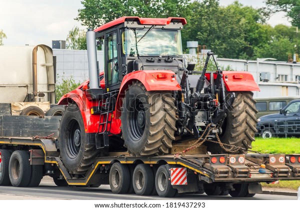 Powerful red tractor on a platform trailer\
road transportation