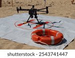 Powerful rescue drone in action over the beach, flying to save lives by lifting a lifebuoy to assist drowning individuals in the sea.