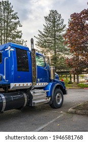 Powerful Shiny Big Rig Semi Truck Tractor In Blue With Painted Aluminum Fuel Tanks And Steps And Back Cab Compartment For Truck Driver Rest Standing On The Parking Lot In Sunshine