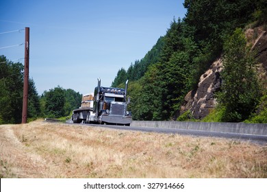 Powerful Spectacular Professional Commercial Classic Dark Blue Semi - Truck With An Open Trailer Flat Bed And Chrome Accents Transports Building Boards On The Highway Near The Picturesque Cliffs.