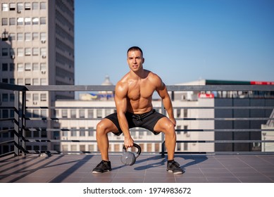 Powerful Sport Man Lifting Up A Heavy Kettle Ball In A Gym, Body Building Exercise. Body Building Workout In An Outdoor Gym.