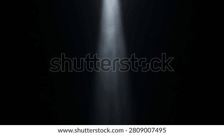 A powerful spotlight illuminates a dark space with a single beam of light. The light source is not visible, creating a dramatic effect.