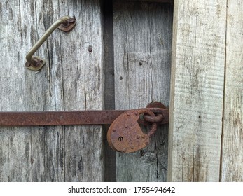 Powerful Steel And Rusty Closed Padlock On A Wooden Barn Door